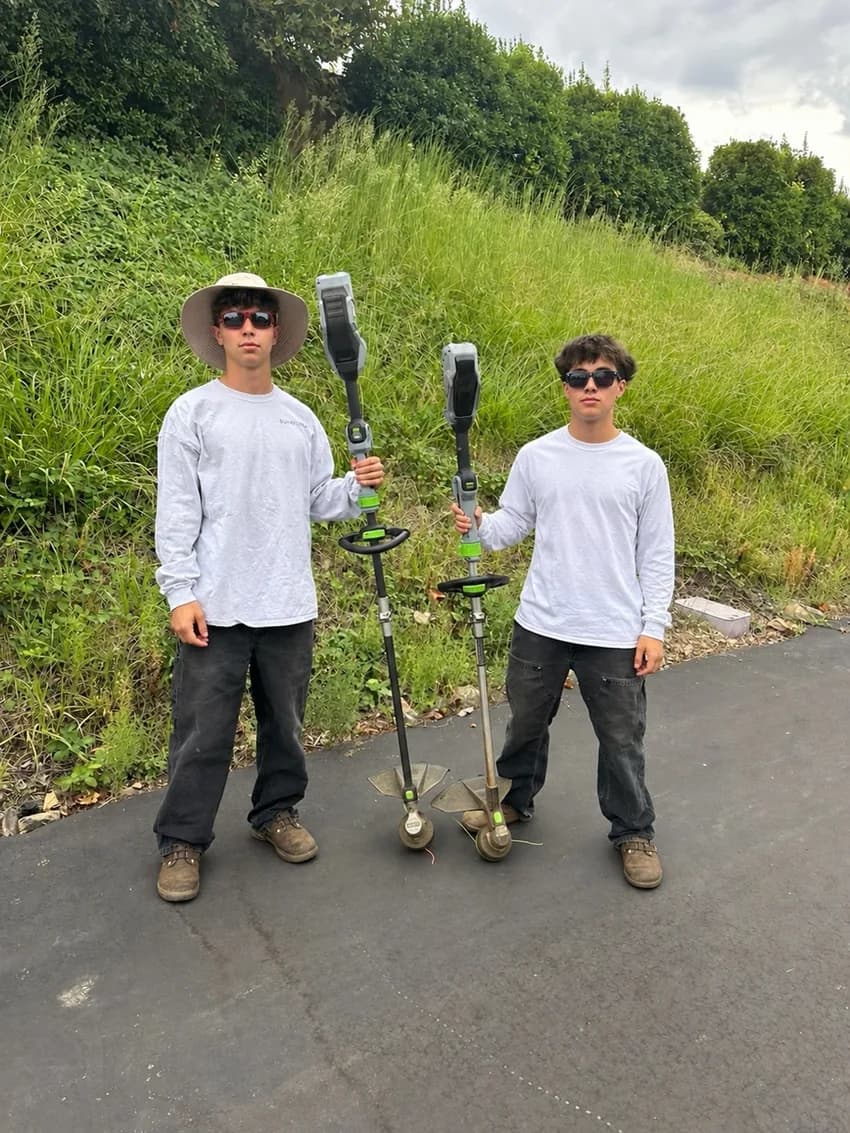 The two B&G founders holding their landscaping tools