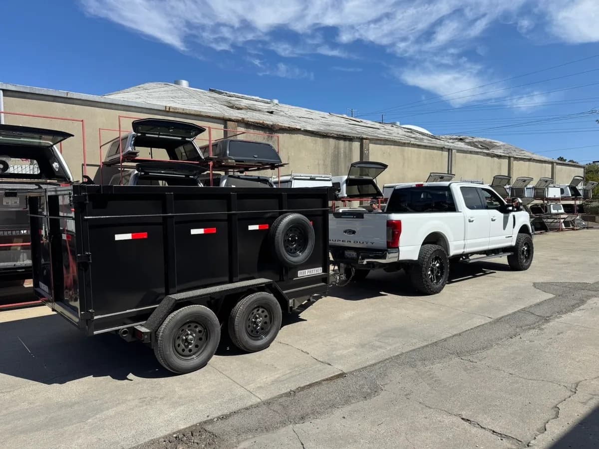 A white pickup truck attached to a black utility trailer